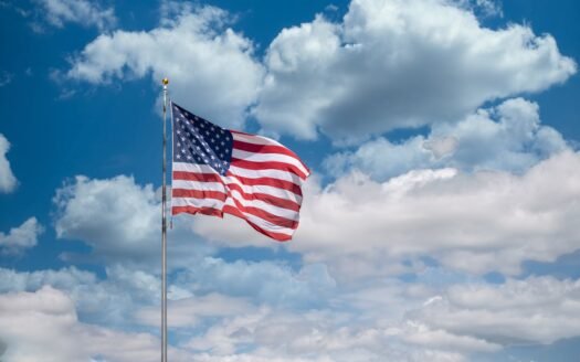 American flag waving under blue sky and white clouds